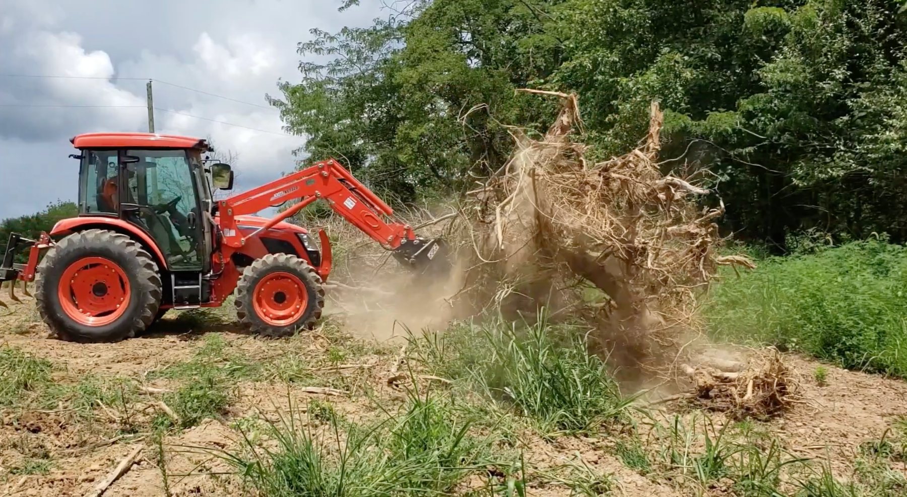 Tractor removing woody brush and root debris