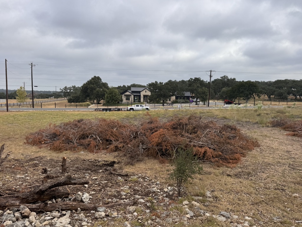 Large piles of cut cedar and brush before forestry mulching on a Boerne property in Kendall County