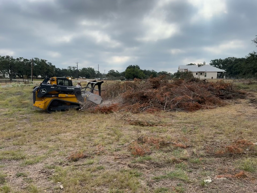 Forestry mulcher processing a pile of cut cedar and brush on a Boerne property in Kendall County